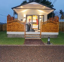 A small cabin with a wooden porch and steps leading up to a glass door at Benone Cabin in Magilligan near Castlerock
