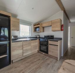 A kitchen with wooden cabinets and appliances at Billy’s Way - Hayling Island