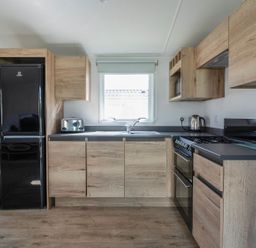 A kitchen with wooden cabinets and appliances at Billy’s Way - Hayling Island