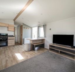 A living room with a television and kitchen area at Sand and Splash - Hayling Island