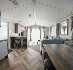 A living room with kitchen area and dining table at Wavecrest - Hayling Island