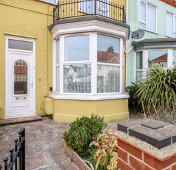 The exterior front of a yellow terraced house with a white door and bay window at 34 North Denes Road in Great Yarmouth
