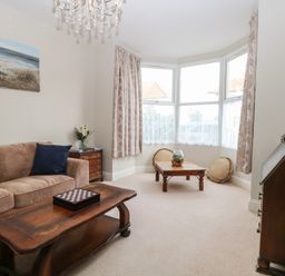 A living room with a brown sofa cushions wooden coffee tables and a bay window at 34 North Denes Road Great Yarmouth