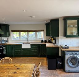 A kitchen with green cabinets white appliances wooden countertops and a wooden table at Hafod Lodge in Hensol near Pontyclun