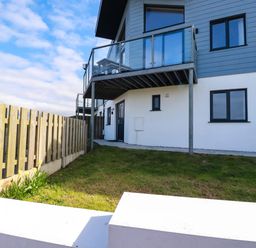 An exterior view of a modern house with a balcony and a wooden fence at Jacana in Perranporth