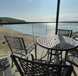 An outdoor seating area with a table and chairs overlooking the beach at 12 Burgh Island Causeway Bigbury-On-Sea