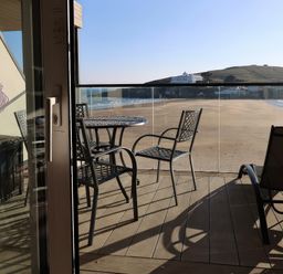 A balcony with chairs and a table overlooking the beach at 12 Burgh Island Causeway Bigbury-On-Sea