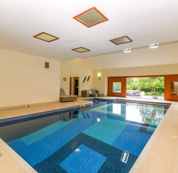 An indoor swimming pool with large windows and seating at Heathcliffe House, Castleton near Cardiff