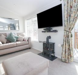 A living room with a sofa cushions a wall mounted television and a stove at Swifts Reach Lodge Kirkstone 10 Limefitt Park near Windermere