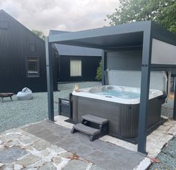 A hot tub under a pavilion in an outdoor area at Grove Cottage in Gladestry