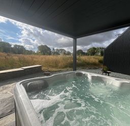 A hot tub next to a stone wall at Grove Cottage in Gladestry