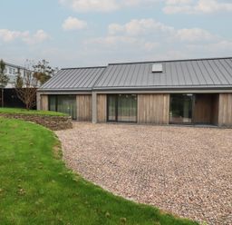 A modern house with gravel driveway and lawn at Harberton