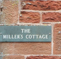 A plaque with the name The Miller's Cottage on a stone wall at Millers Cottage in Seaville near Wigton