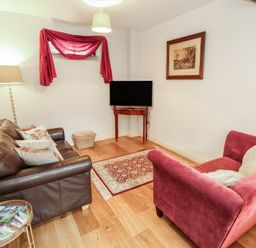 A living room with a sofa and a television at Millers Cottage Seaville near Wigton