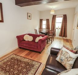 A living room with a sofa and dining table at Millers Cottage in Seaville near Wigton