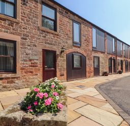 An outdoor area with a flowerbed and a building at The Coach House near Wigton