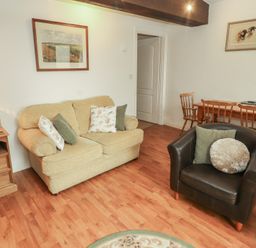 A living room with a sofa, lamp, and dining table at The Coach House near Wigton