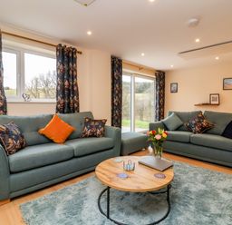 A living room with two sofas a round wooden coffee table and patterned curtains at Hideaway in Great Torrington
