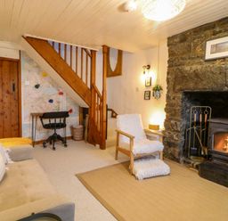 A living room with a fireplace and staircase at Waterfall Retreat in Blaenau Ffestiniog
