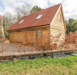 A wooden outbuilding with a red tiled roof and two skylights surrounded by small trees and grass at Pheasants Rise Apartment in Ross-On-Wye
