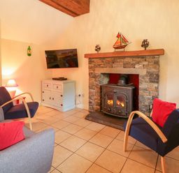 A living room with a fireplace and television at Shane's Cottage in Falcarragh, County Donegal
