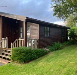 A wooden cabin with steps and lawn at Island View Lodge Back of Keppoch near Arisaig