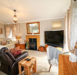 A living room with sofas and a TV beside a fireplace at The Lake House in Marston near Barkston