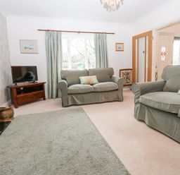 A living room with two sofas a television on a wooden stand and a window with curtains at Kerangarth in Corbridge