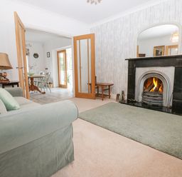 A living room with a fireplace a green sofa and an open doorway leading to a dining area at Kerangarth in Corbridge