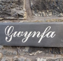 A stone wall with a black sign that reads Gwynfa at Gwynfa in Ysbyty Ifan