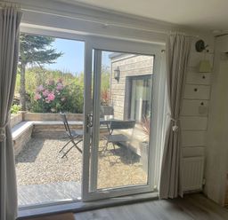 A living room with a view of the garden at The Cow Shed in Mawgan Porth