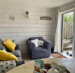 A living room with a sofa and armchair at The Cow Shed in Mawgan Porth