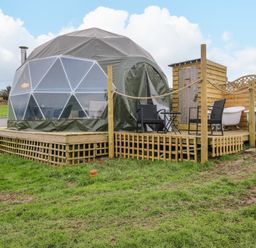 A dome tent on a wooden platform with outdoor chairs and clawfoot bathtubs at Meadow View - Bryn-Mawr Retreat in Brynmawr near Llanymynech