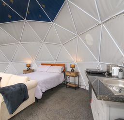 A dome-shaped room with a bed two bedside tables a sofa and a kitchenette at Meadow View - Bryn-Mawr Retreat in Brynmawr near Llanymynech