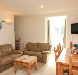 A living room with brown leather sofas a wooden coffee table and a dining table with chairs and flowers at Millers Loft in Modbury