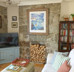 A living room with a television and a stone wall at Kittiwake Newlyn