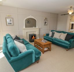 A living room with two teal sofas a wooden coffee table and a fireplace at 2 Summers Way Moreton-In-Marsh