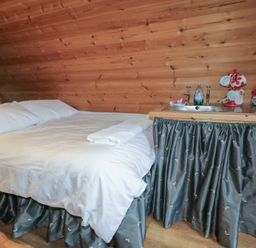 A bedroom with a white bed next to a small kitchen sink area with teacups and containers at River View Pod near Muff County Donegal