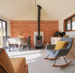 A dining area with table and chairs a wood burning stove and a rocking chair in a room with patterned floor tiles at Beech Tree Cabin in Goodmanham near Market Weighton