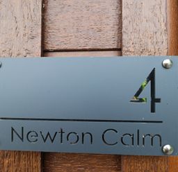 An address plaque with number 4 and Newton Calm at Newton Ferrers