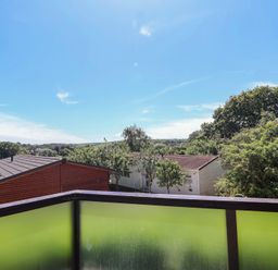A view from a balcony showing houses and trees at Skyview in Newton Ferrers