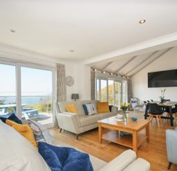 A living room with sofas, a coffee table, a dining table, and sliding glass doors showing an outdoor area at Atlanta near Tintagel