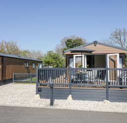 A small wooden cabin with a fenced deck patio and outdoor furniture at Casa De Rhu in Evesham