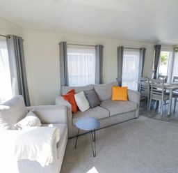 A living room with a gray sofa and armchair a small round table and a dining table with chairs at Casa De Rhu in Evesham