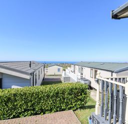 A row of static caravans with a hedge in front and a view of the sea at 21 Bay View in Maenygroes near New Quay Ceredigion