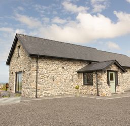 A house with stone exterior and patio furniture at Golygfa Cwrt Near Bontgoch and Penrhyncoch