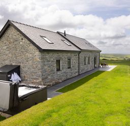 A stone house with a hot tub and outdoor furniture at Golygfa Cwrt Near Bontgoch and Penrhyncoch