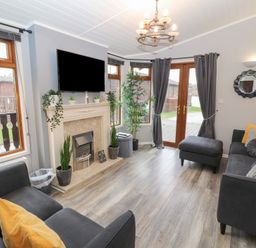 A living room with sofas a fireplace plants and a television at Lakeside 18 in Carnforth