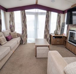 A living room with sofas a coffee table a wall-mounted television and a fireplace at Hazel Park 11 HP11 in Rhyl
