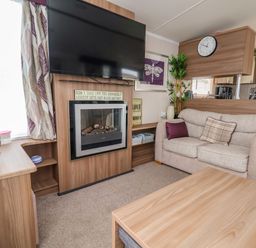 A living room with a sofa cushions fireplace tv and a wooden coffee table at Hazel Park 11 HP11 in Rhyl